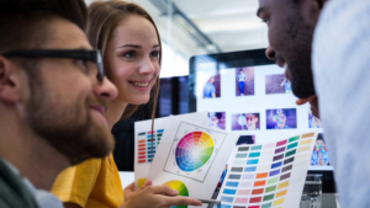Group of graphic designers choosing color from color chart in office